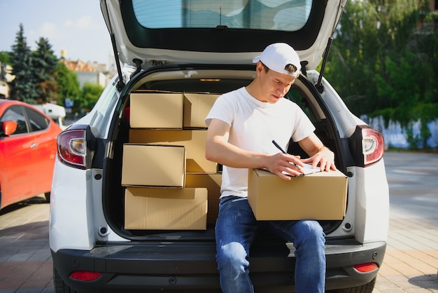 Giovane fattorino che controlla la lista negli appunti in auto