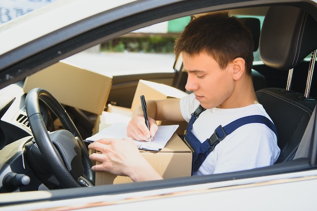 Giovane fattorino che controlla la lista negli appunti in auto