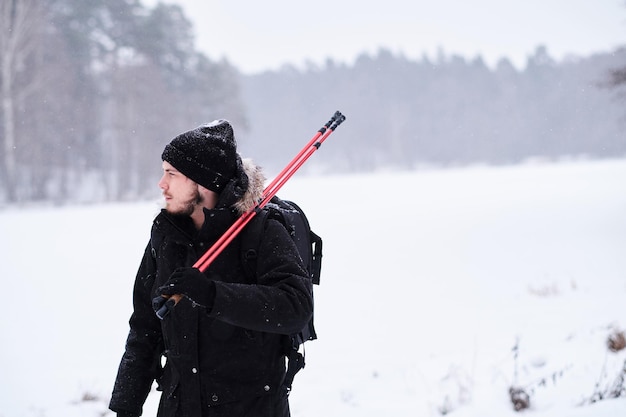 Giovane felice che fa trekking accanto a una foresta innevata