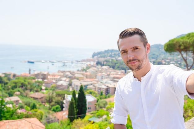 Giovane felice che prende selfie sulla vecchia città costiera Rapallo in Liguria