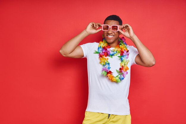 Giovane felice con una collana hawaiana su uno sfondo rosso