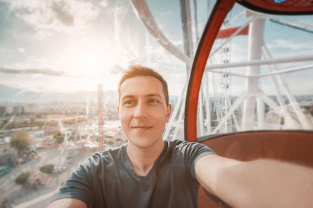 Giovane felice ed eccitato che scatta una foto selfie nella cabina di una ruota panoramica Avventure di viaggio da soli e parco divertimenti