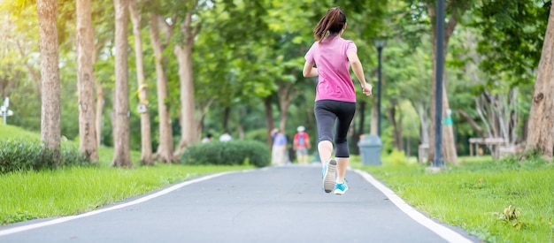 Giovane femmina adulta in abiti sportivi in esecuzione nel parco all'aperto