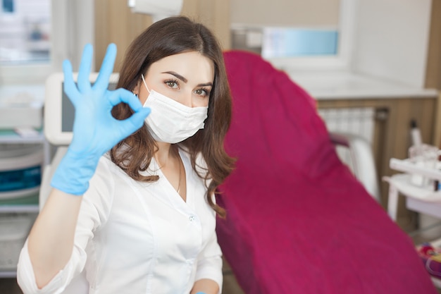 Giovane femmina attraente medico al chiuso. Ritratto della donna che indossa uniforme medica nella clinica. Medico con attrezzatura medica. Cosmetologo nel suo salotto