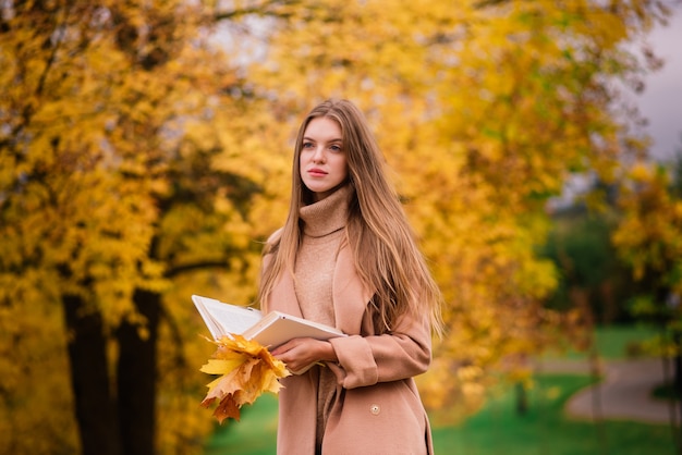 Giovane femmina bionda rossa che cammina nel parco autunnale.