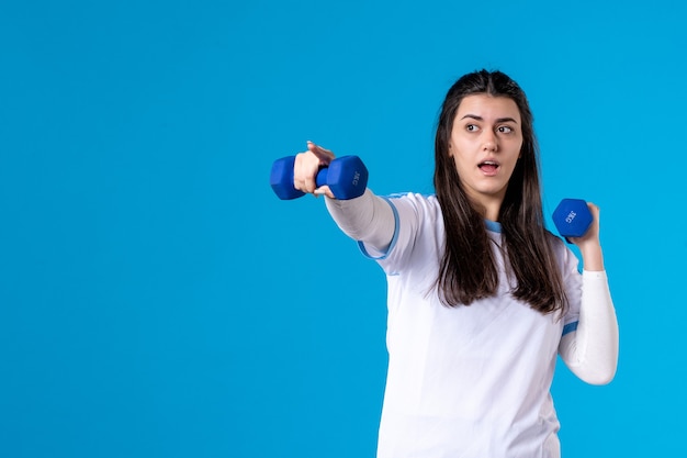 Giovane femmina di vista frontale che tiene i dumbbells blu