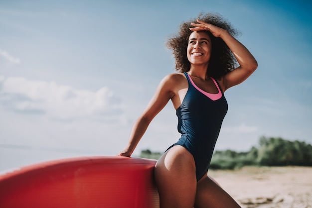 Giovane femmina in costume da bagno magra su surf in spiaggia.