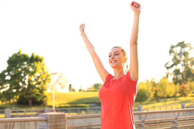 Giovane femmina sorridente che riposa dopo un allenamento fitness attivo nel parco.