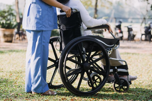 Giovane fisioterapeuta asiatica che lavora con una donna anziana a camminare con un passeggino