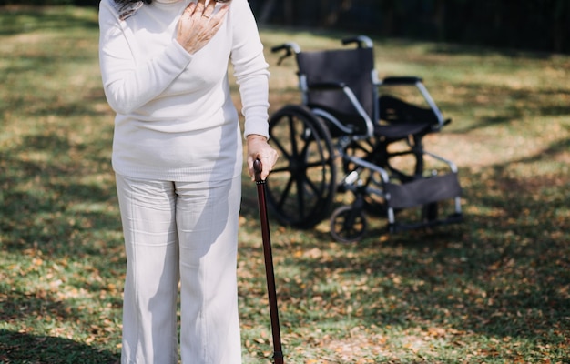 Giovane fisioterapeuta asiatica che lavora con una donna anziana a camminare con un passeggino