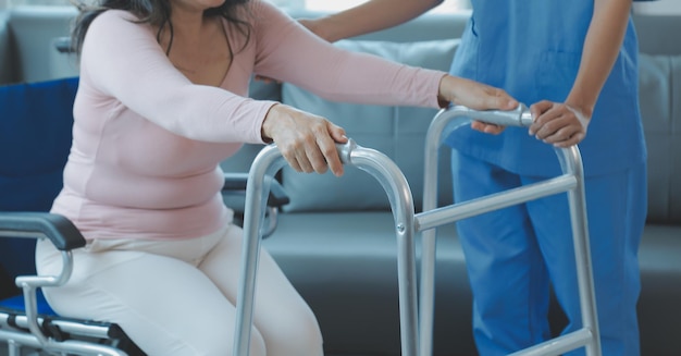 Giovane fisioterapista asiatico che lavora con una donna senior mentre cammina con un deambulatore