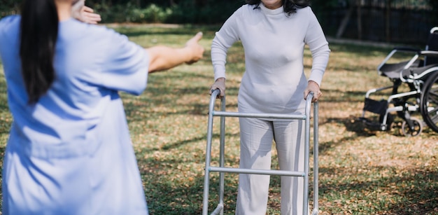 Giovane fisioterapista asiatico che lavora con una donna senior mentre cammina con un deambulatore