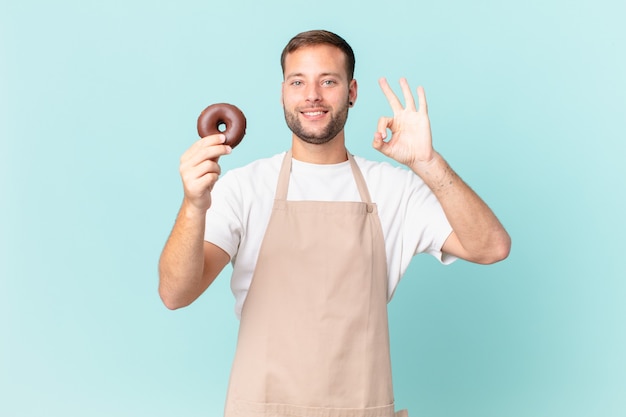 Giovane fornaio bello con una ciambella