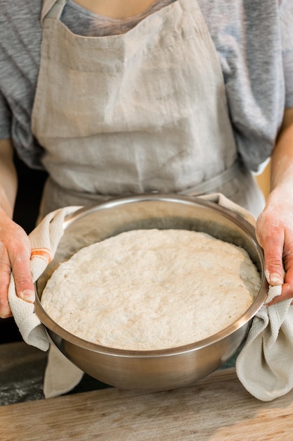 Giovane fornaio che prepara pane a lievitazione naturale artigianale.