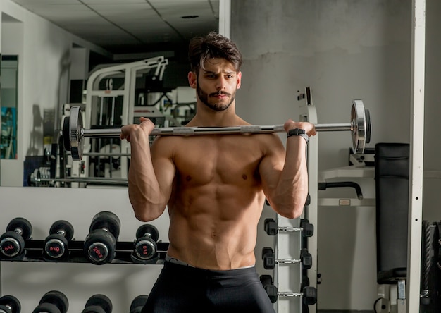 Giovane forte e bello che fa esercizio con i dumbbells