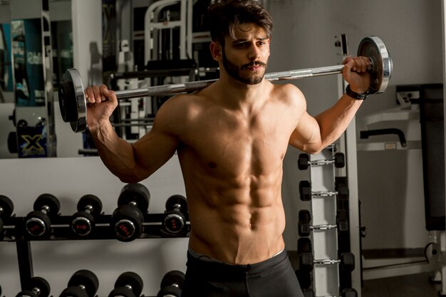 Giovane forte e bello che fa esercizio con i dumbbells