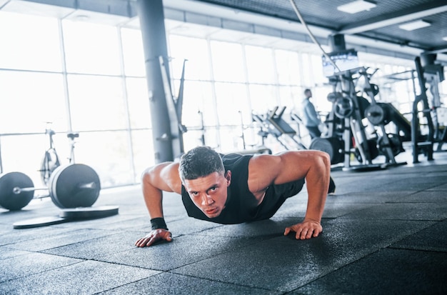 Giovane forte in abiti sportivi che fanno flessioni in palestra