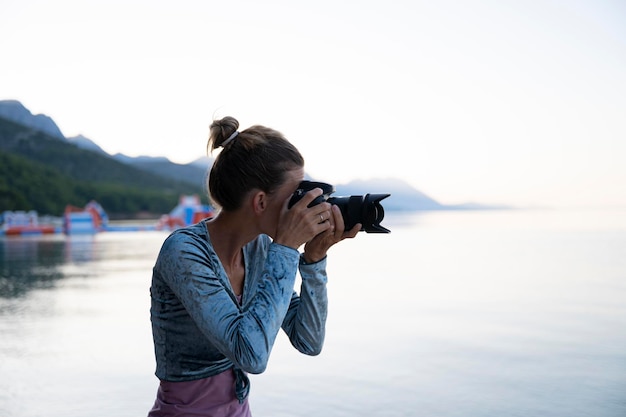 Giovane fotografa femminile che scatta foto in riva al mare