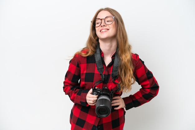 Giovane fotografo bella donna isolata su sfondo bianco in posa con le braccia all'anca e sorridente