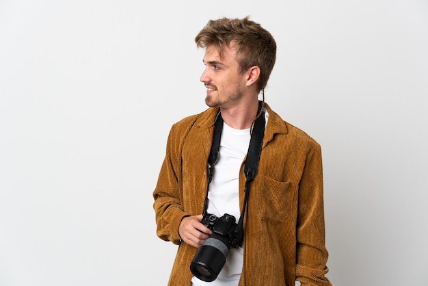 Giovane fotografo biondo uomo isolato su sfondo bianco alla ricerca di lato