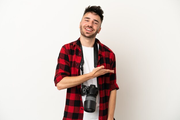 Giovane fotografo caucasico uomo isolato su sfondo bianco che presenta un'idea mentre guarda sorridendo verso