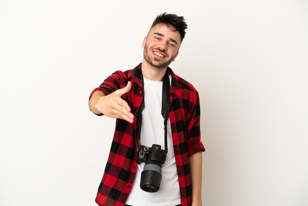 Giovane fotografo caucasico uomo isolato su sfondo bianco che stringe la mano per chiudere un buon affare