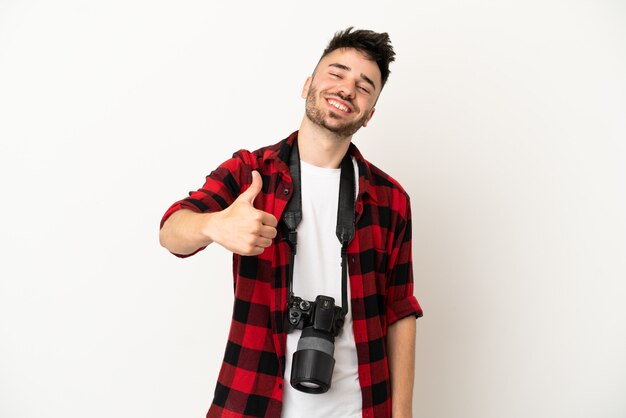 Giovane fotografo caucasico uomo isolato su sfondo bianco con il pollice in alto perché è successo qualcosa di buono