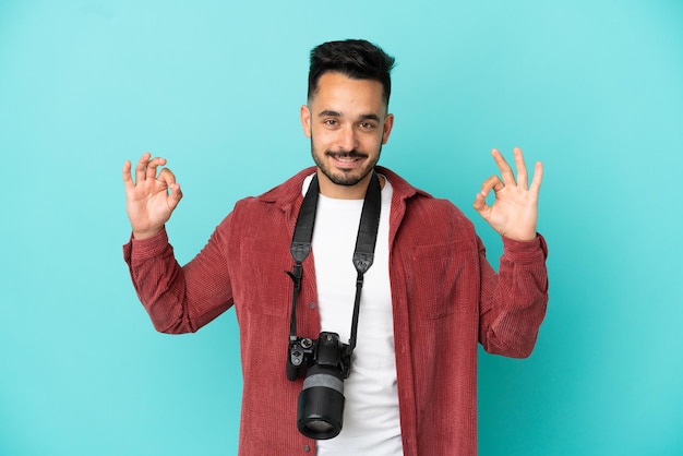 Giovane fotografo caucasico uomo isolato su sfondo blu che mostra un segno ok con le dita