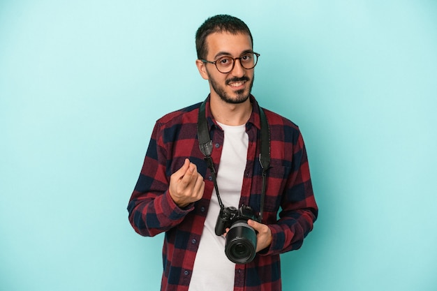 Giovane fotografo caucasico uomo isolato su sfondo blu che punta con il dito su di te come se invitasse ad avvicinarsi.