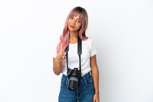 Giovane fotografo di razza mista donna con capelli rosa isolato su sfondo bianco che mostra e solleva un dito