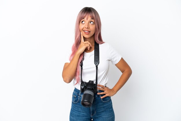 Giovane fotografo di razza mista donna con capelli rosa isolato su sfondo bianco pensando a un'idea mentre guarda in alto