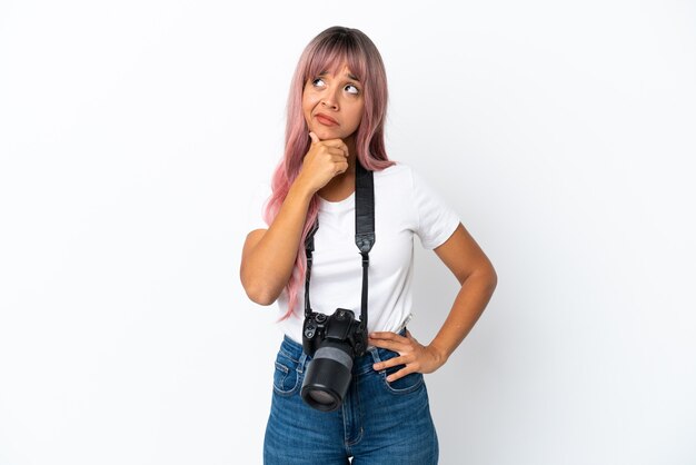 Giovane fotografo di razza mista donna con i capelli rosa isolato su sfondo bianco avendo dubbi