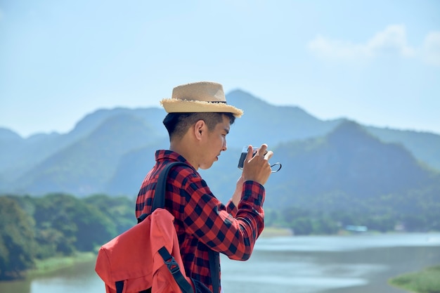 Giovane fotografo di viaggio asiatico a scattare foto all'aperto