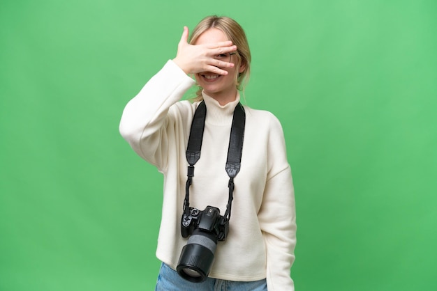 Giovane fotografo donna inglese su sfondo isolato che copre gli occhi con le mani e sorridente