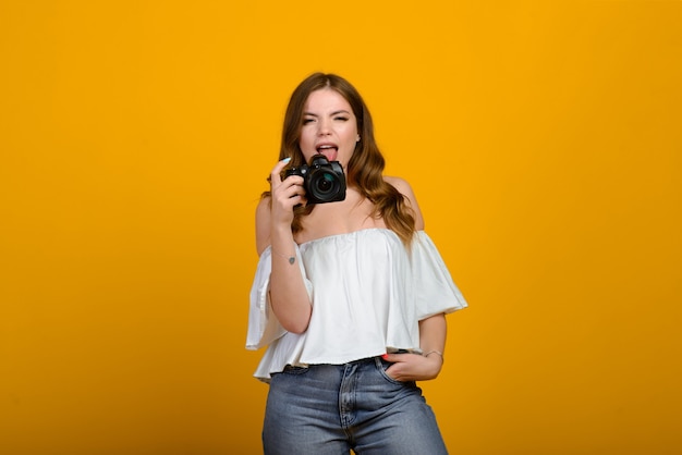 Giovane fotografo femminile con fotocamera su giallo