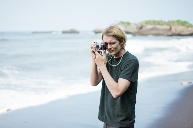 Giovane fotografo maschio bello sulla spiaggia