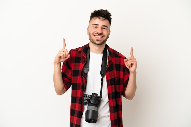 Giovane fotografo uomo caucasico isolato su sfondo bianco che punta verso l'alto una grande idea