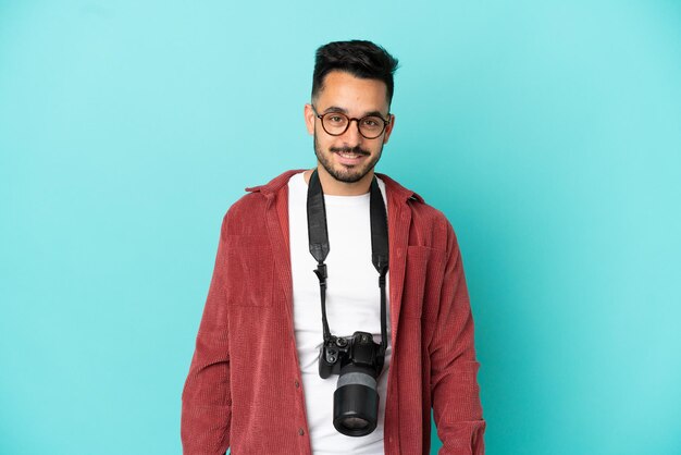 Giovane fotografo uomo caucasico isolato su sfondo blu con gli occhiali e felice