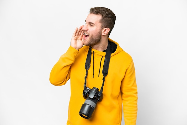 Giovane fotografo uomo su sfondo bianco isolato gridando con la bocca spalancata al laterale