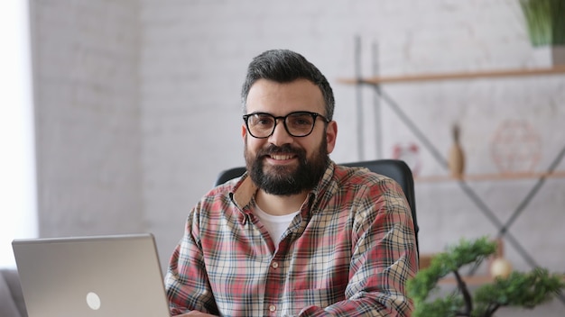 giovane freelance maschio bello che lavora con il laptop seduto a casa. educazione online, lavoro a distanza.