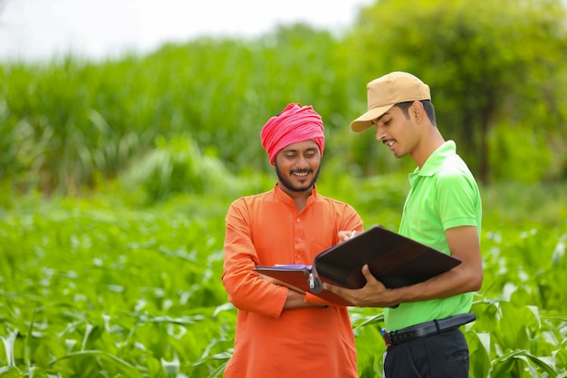 Giovane funzionario di banca dell'India che completa il lavoro di ufficio con gli agricoltori al campo di agricoltura.