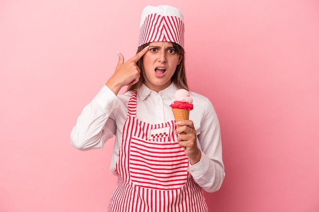 Giovane gelatiera donna che tiene il gelato isolato su sfondo rosa che mostra un gesto di delusione con l'indice.