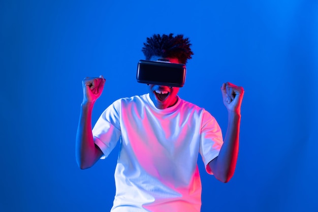 Giovane giocatore afroamericano che indossa VR solleva il pugno per vincere il gioco