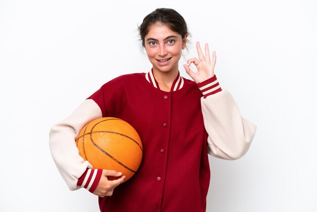 Giovane giocatore di basket donna isolata su sfondo bianco che mostra il segno ok con le dita