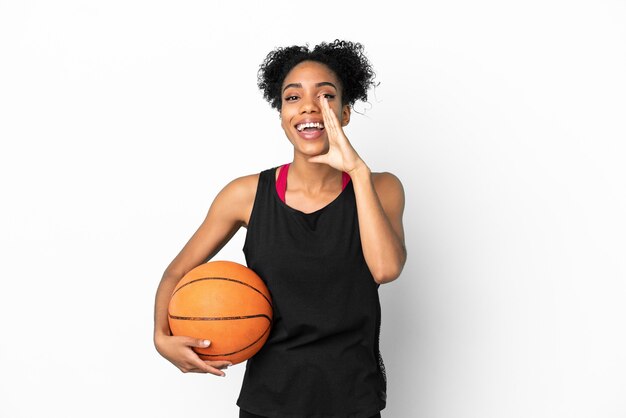 Giovane giocatore di basket donna latina isolata su sfondo bianco che grida con la bocca spalancata