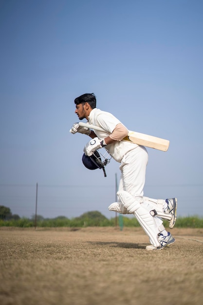 Giovane giocatore di cricket indiano che entra nel campo di cricket concetto di cricket e sport indiano