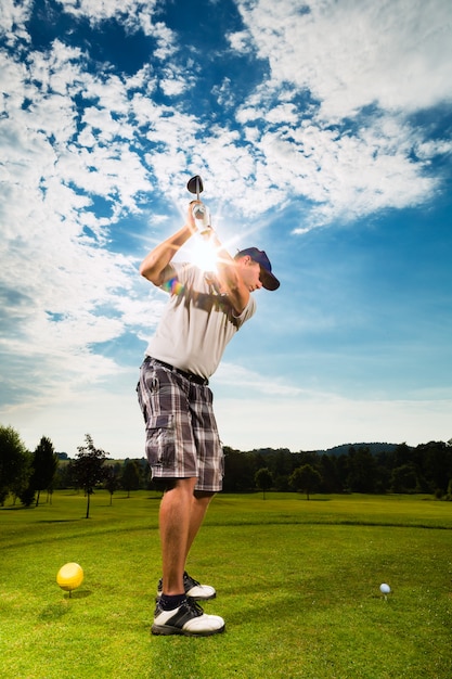 Giovane giocatore di golf sul corso che fa l'oscillazione di golf