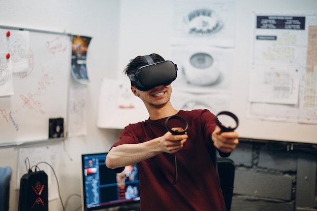 Giovane giocatore in occhiali per realtà virtuale, auricolare per occhiali VR con joystick.