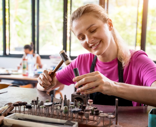 Giovane gioielliere femminile che fa gioielli in officina