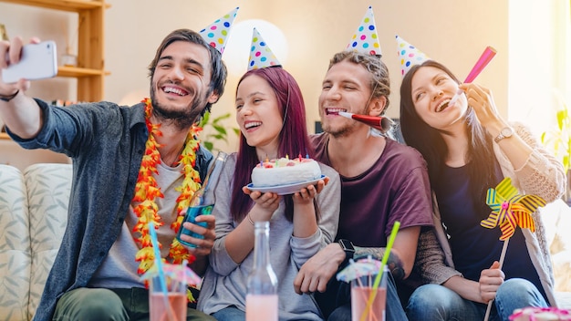 Giovane gruppo di amici felici che festeggiano il compleanno e fanno foto selfie